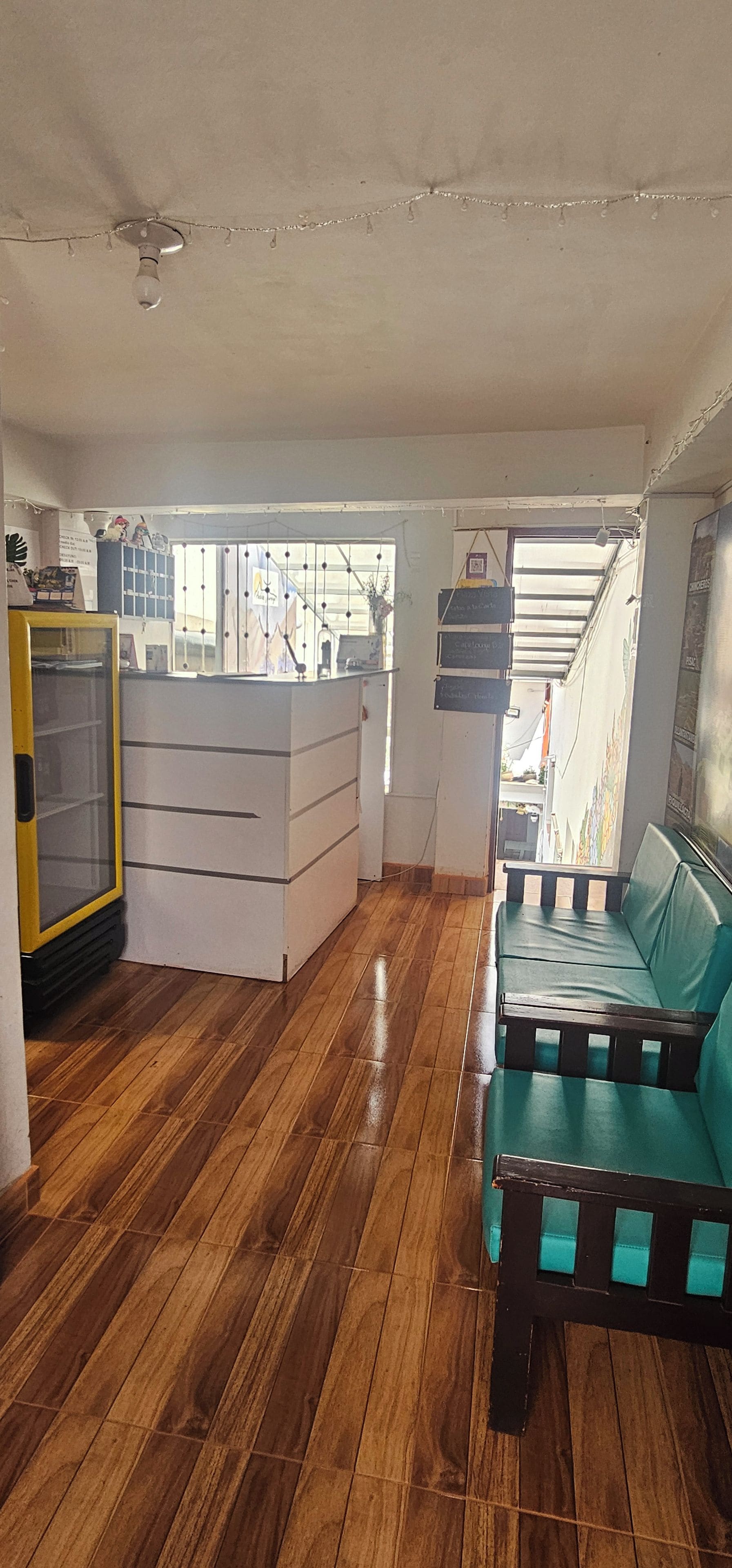 A room with a wooden floor, a white desk, a green sofa, and a yellow cabinet.