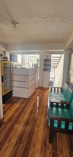 A room with a wooden floor, a white desk, a green sofa, and a yellow cabinet. - CUSCO VISTA GUETS HOUSE (Cusco)