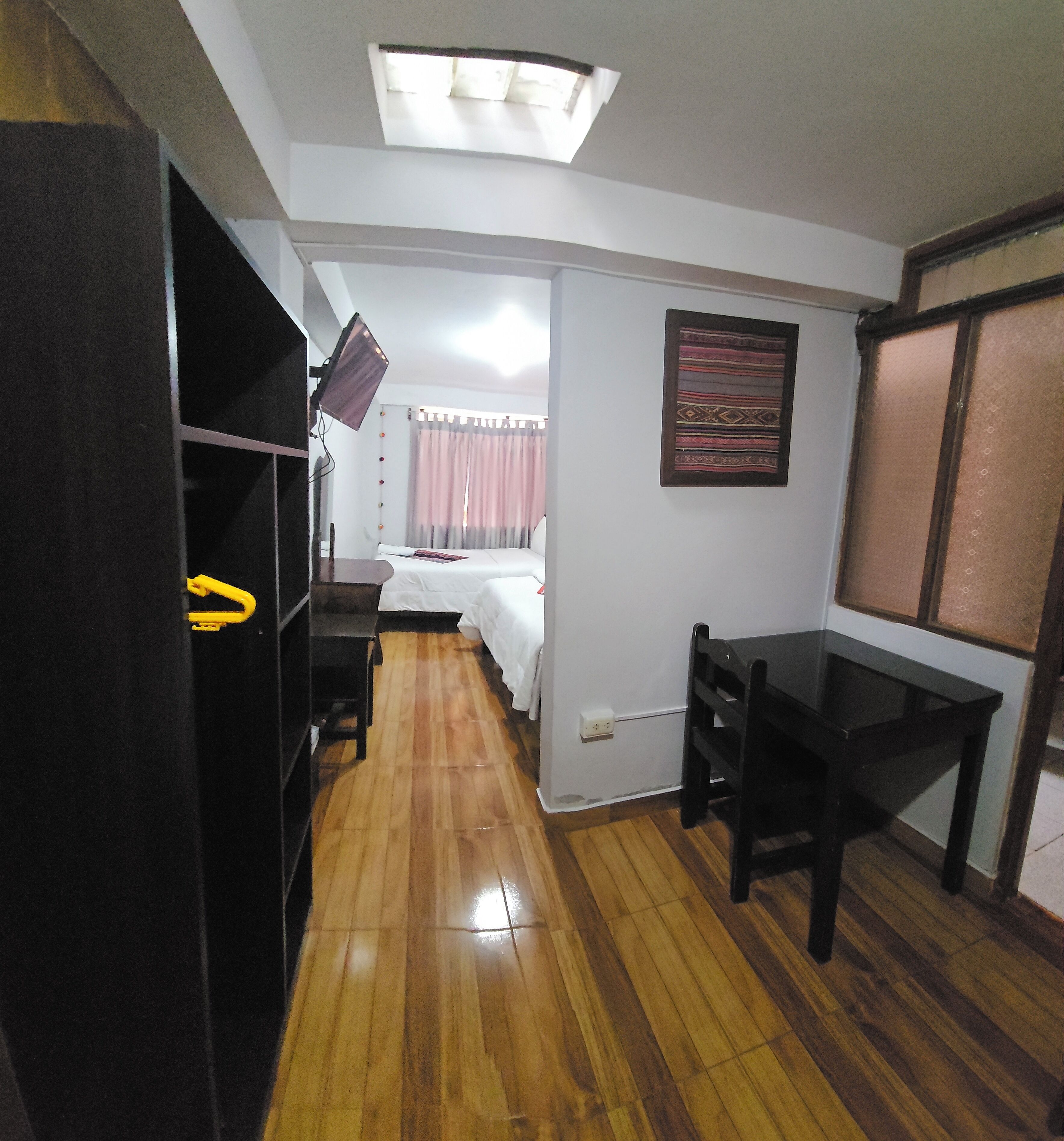 Una habitación con cama, escritorio, armario y una lámpara en el techo.