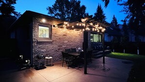 A stone building with a patio, outdoor seating, and string lights.