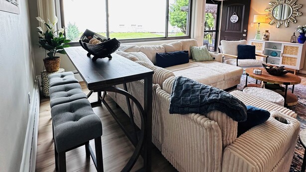 A modern living room with a sofa, a dining table, and a large window.
