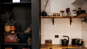 A kitchen with a dark wooden bookshelf, a white tiled backsplash, and a black toaster. - the tiny burrow ~ magical fleurieu escape (Aldinga)