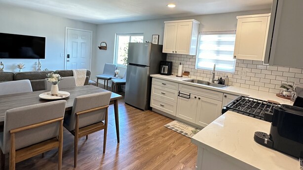 Una cocina moderna con armarios blancos, estufa integrada y un comedor con mesa y sillas.