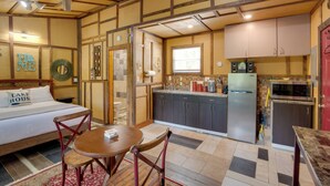 Una habitación de hotel compacta con una cama, una pequeña mesa de comedor y una kitchenette.