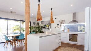 Een moderne keuken met een centraal eiland, witte kasten en hanglampen.