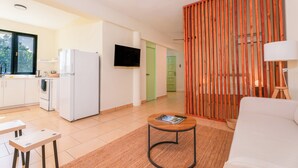 A modern kitchen with white appliances, a dining area with a table and chairs, and a living room with a sofa and a lamp. - Sunny Seaside Getaway (San Juan)