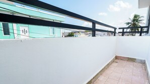A balcony with a tiled floor, a white wall, and a black railing. - Sunny Seaside Getaway (San Juan)
