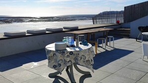 Terraza en la azotea con mesa lista para cenar, con vistas al mar.