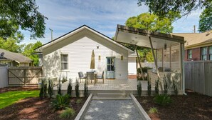 Eenlaags huis met een overdekte veranda, een voordeur en een kleine tuin met planten en grind.