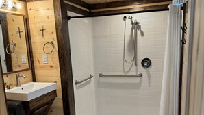 A wooden interior with a shower, sink, and mirror. - Dinosaur Valley RV Park Cabin 6 (Glen Rose)