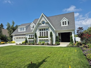 A two-story house with a garage, a front lawn, and a variety of plants and flowers. - Cozy studio in Douglas with swimming pool and fireplace. (Douglas)