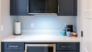 A compact kitchen with dark cabinetry, a stainless steel microwave, and a built-in oven. - Cozy studio in Douglas with swimming pool and fireplace. (Douglas)