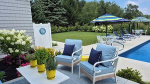 A poolside area with lounge chairs, a table, and potted plants. - Cozy studio in Douglas with swimming pool and fireplace. (Douglas)