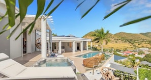 Un espace piscine aménagé sur le toit, avec des chaises longues, un jacuzzi et une vue sur un paysage désertique.
