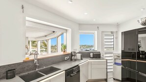A modern kitchen with a large window, a built-in oven, and a coffee maker.