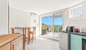 Et moderne køkken med havudsigt, et spiseområde med bord og stole, og en skydedør til et udendørs siddeområde.