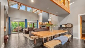 A spacious living area with a large wooden dining table, a fireplace, and a view of the outdoors.