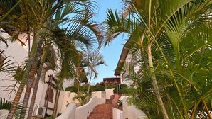 Una escalera de ladrillo rojo y paredes blancas, rodeada de palmeras.