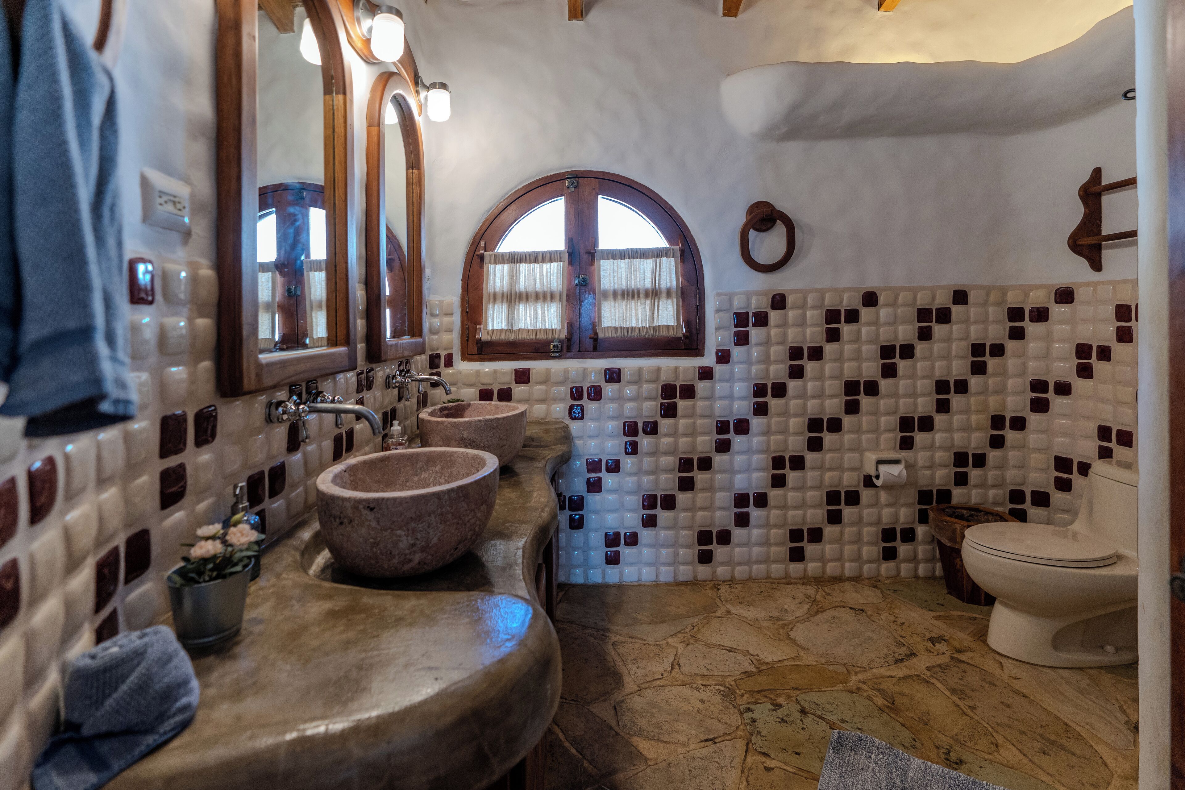 A bathroom with a stone sink, a mirror, and a toilet.