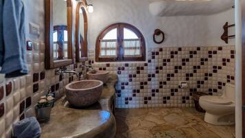 A bathroom with a stone sink, a mirror, and a toilet.