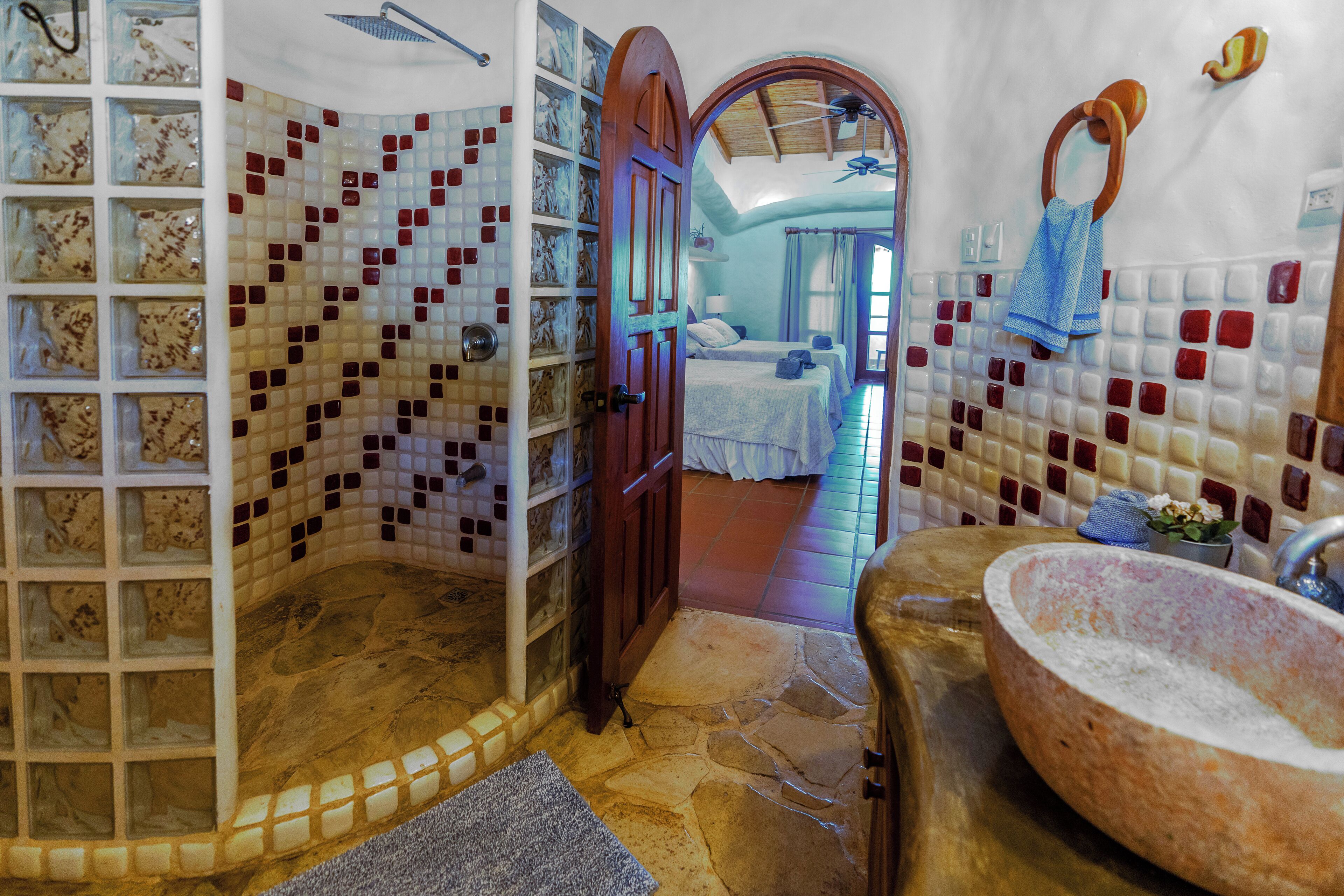 Une salle de bain avec des murs recouverts de mosaïques, un lavabo en pierre et un espace douche.