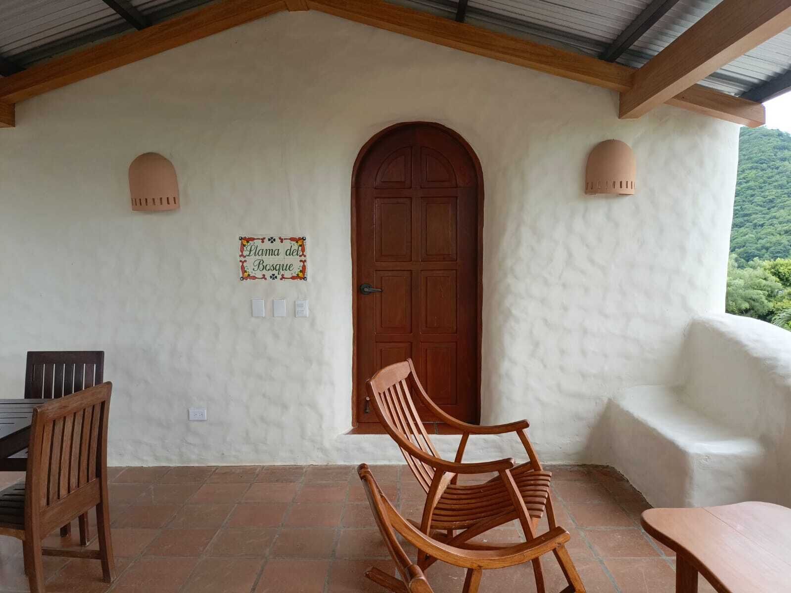 A rustic wooden door with a sign above it, a wooden rocking chair, and a bench.