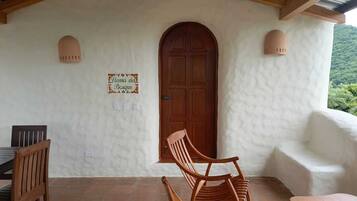 A rustic wooden door with a sign above it, a wooden rocking chair, and a bench.