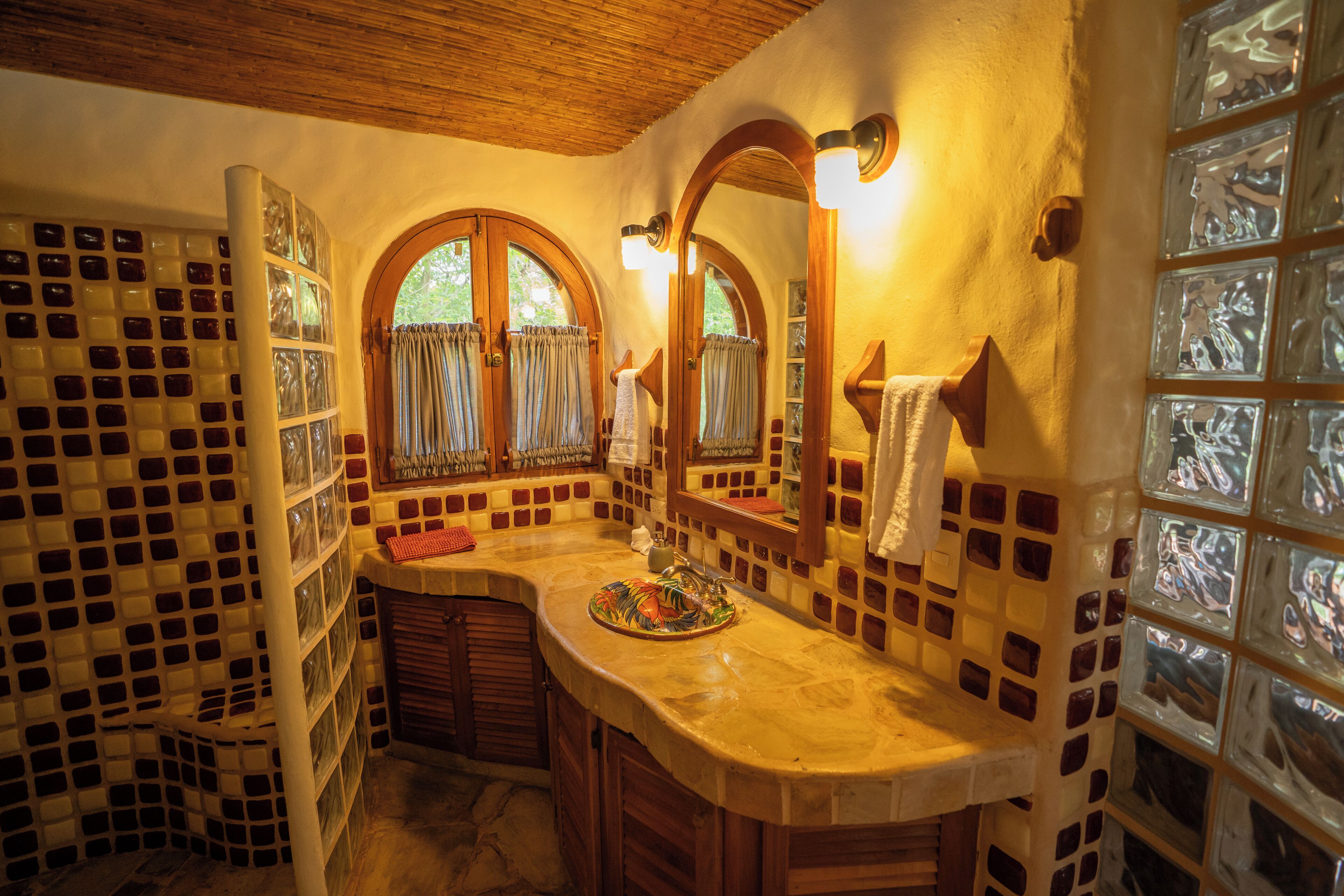 A bathroom with a curved vanity, a mirror, and a tiled wall.
