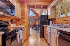 Eine Holzhütte mit einer Küche, ausgestattet mit Herd, Mikrowelle, Kühlschrank und Holzschränken.