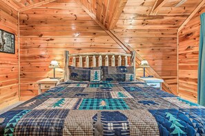 A wooden cabin bedroom with a bed, nightstands, and a window. - Secluded Cabin with 2 En Suites & Hot Tub (Gatlinburg)