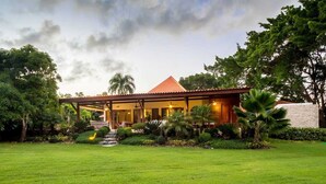 Ein Haus mit rotem Dach, umgeben von üppigem Grün und einem gepflegten Rasen.