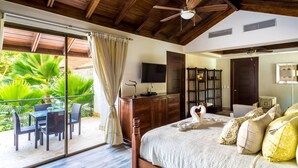 Ein Schlafzimmer mit Bett, Fernseher, Holzschrank, Deckenventilator und einem Balkon mit Gartenmöbeln.