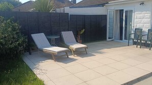 Une terrasse avec deux fauteuils de jardin, une petite table et un pot de fleurs.