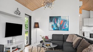 Ein modernes Wohnzimmer mit einem Flachbildfernseher, einem Ecksofa, einem Couchtisch und einem großen abstrakten Gemälde.