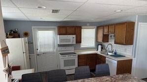 A compact kitchen with a refrigerator, microwave, stove, sink, and wooden cabinets. - Relax in Waupaca and the Chain O Lakes. (Waupaca)