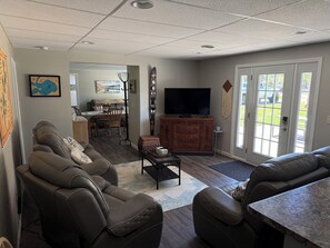 A living room with leather sofas, a flat-screen TV, and a dining area with a table and chairs. - Relax in Waupaca and the Chain O Lakes. (Waupaca)