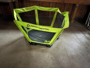 A trampoline with a bright green safety net and the brand name "PaddlesMash" visible.