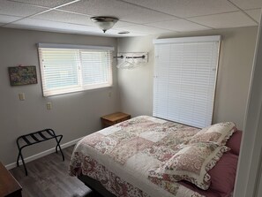 A bedroom with a bed, a nightstand, a chair, a window with blinds, and a ceiling fan.