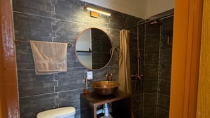A bathroom with a toilet, a sink with a copper basin, a mirror, and a shower. - Pet Friendly Luxury Depa in Bugambilias (Zapopan)