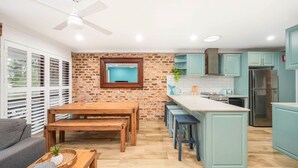 Una cocina moderna con pared de ladrillo, mesa de comedor de madera y armarios azul claro.