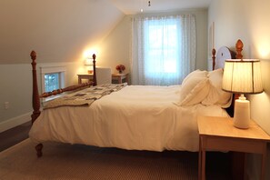 Quarto com cama de dossel, mesa de cabeceira com abajur e janela com cortinas.