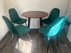 En matplats med ett runt bord och fyra stolar i turkos färg.