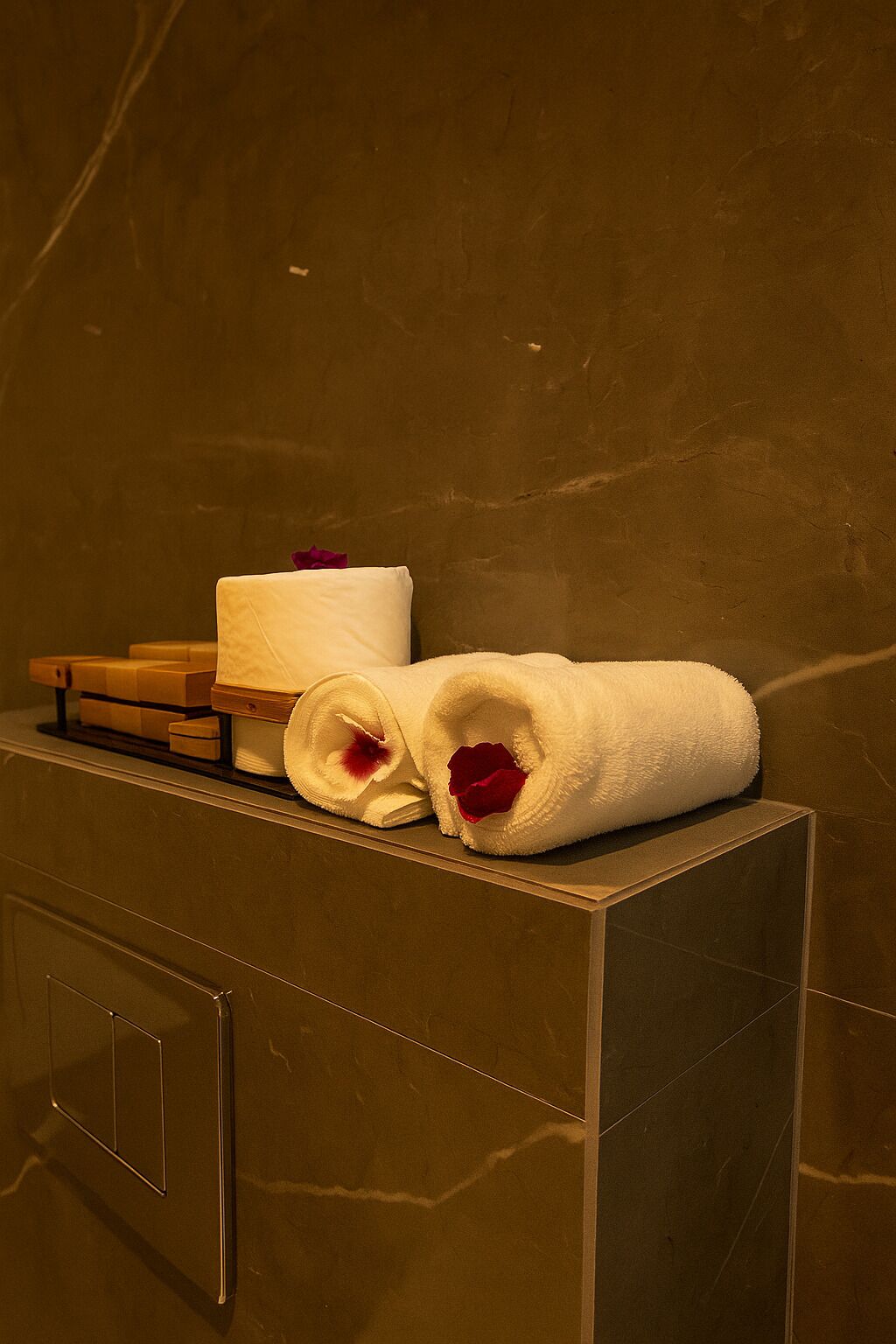 Un baño con encimera de mármol, un perchero con toallas dobladas y un caja de madera.