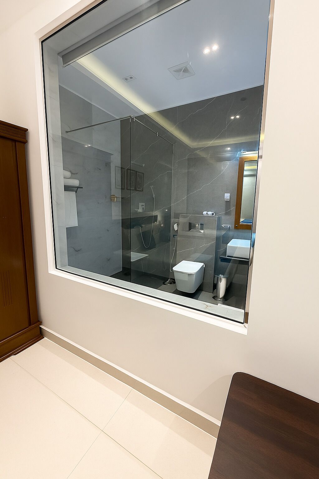 Een moderne badkamer met een groot raam, een douche, toilet en wastafel.