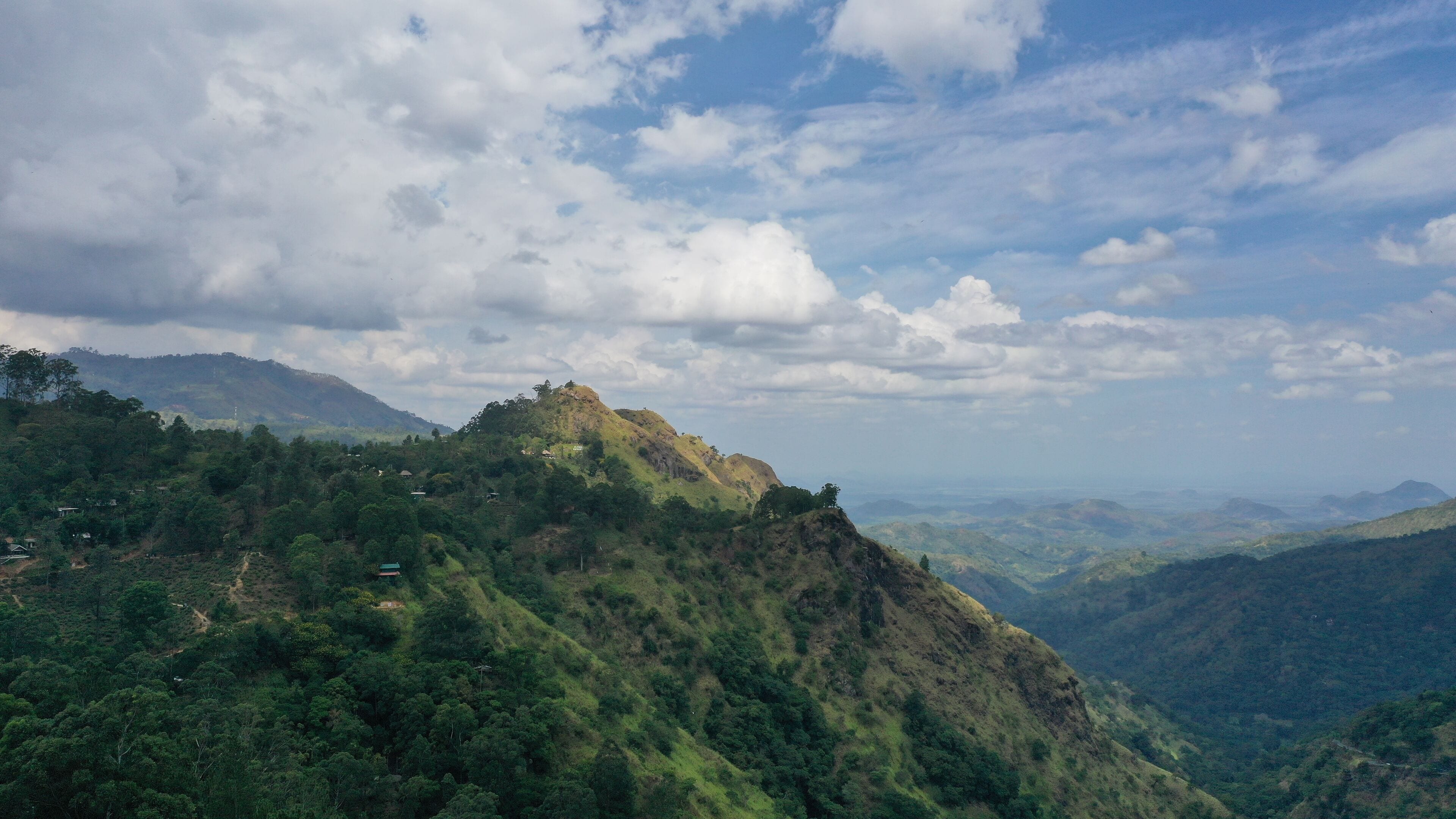 A mountainous landscape with lush greenery and scattered buildings.