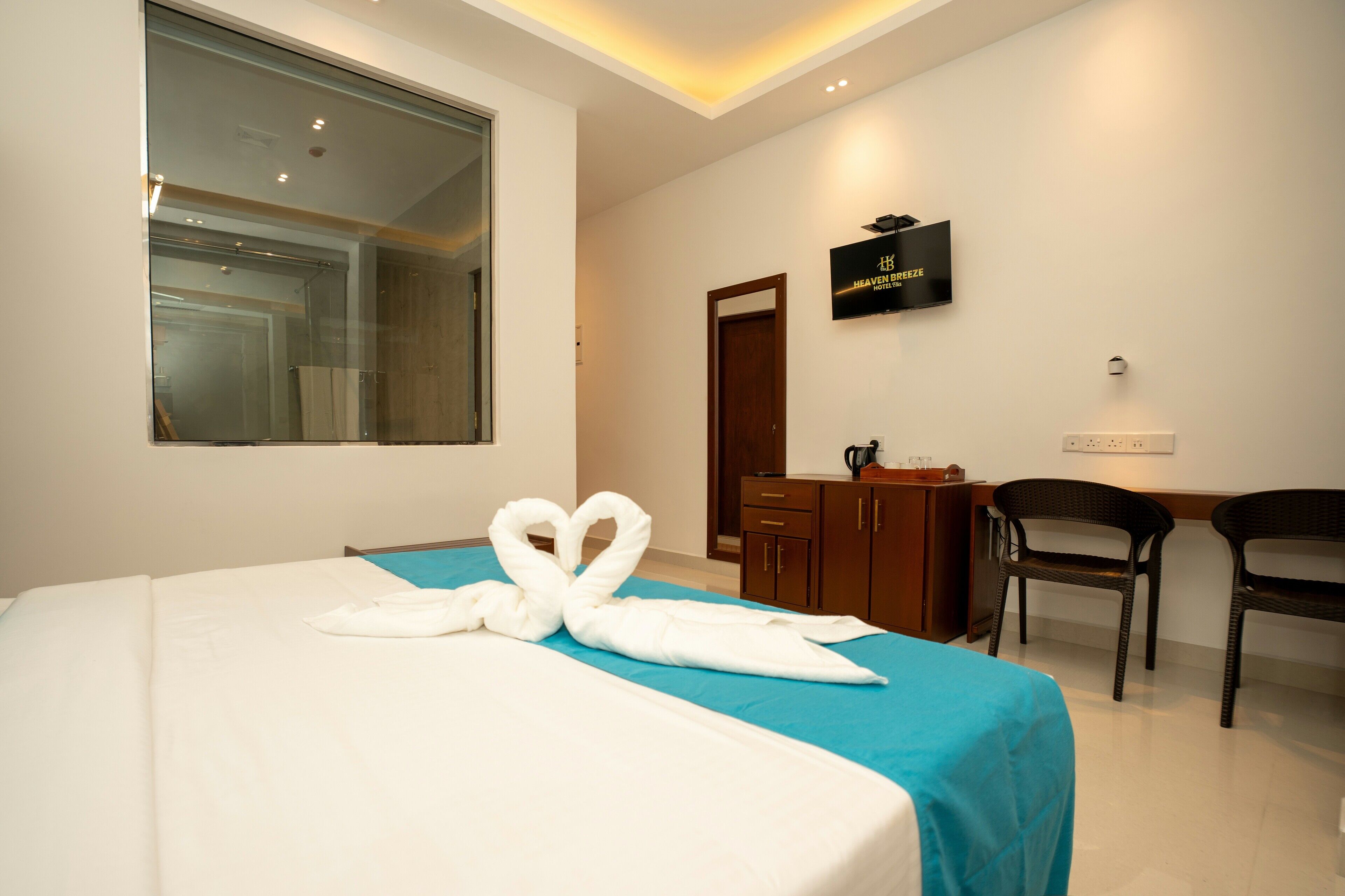 A hotel room with a bed, a desk, a chair, a TV, and a mirror.