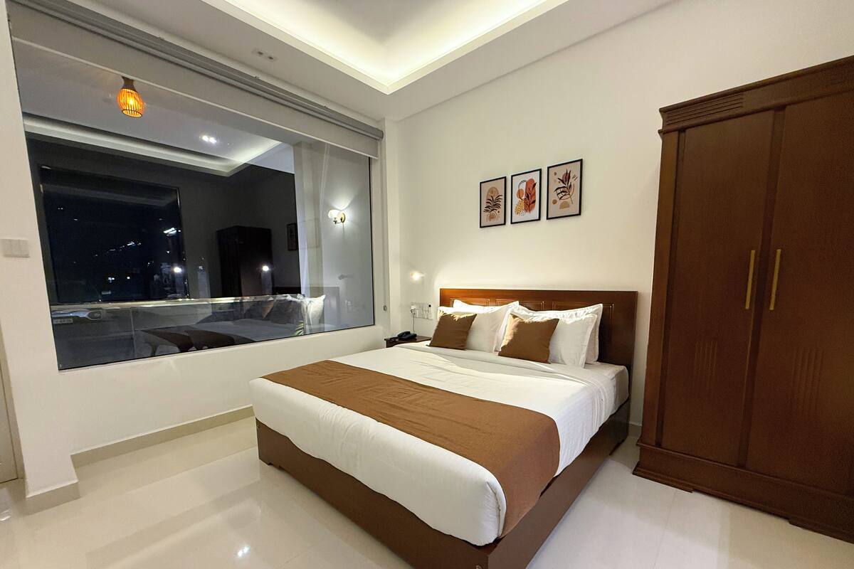 Un dormitorio moderno con una cama grande, un armario y una ventana con vista a la ciudad.