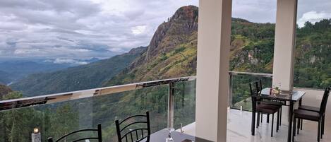 Un comedor con mesa y sillas, con vista a un paisaje montañoso y una perspectiva despejada del valle y las montañas al fondo.