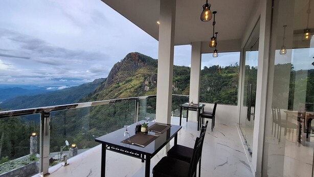 Un comedor moderno con barandilla de vidrio que da a un paisaje montañoso.
