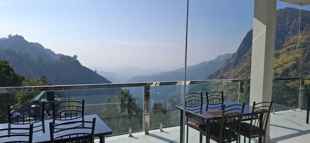 Una terrazza con tavoli e sedie, che si affaccia su un paesaggio montuoso.